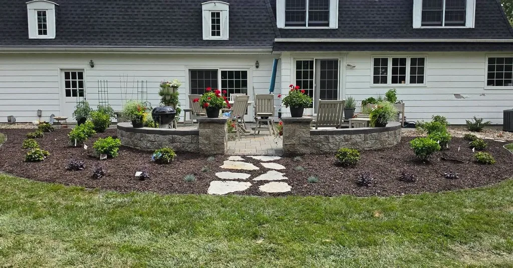 Planting bed with shrubs and a stepping-stone path beside a white house