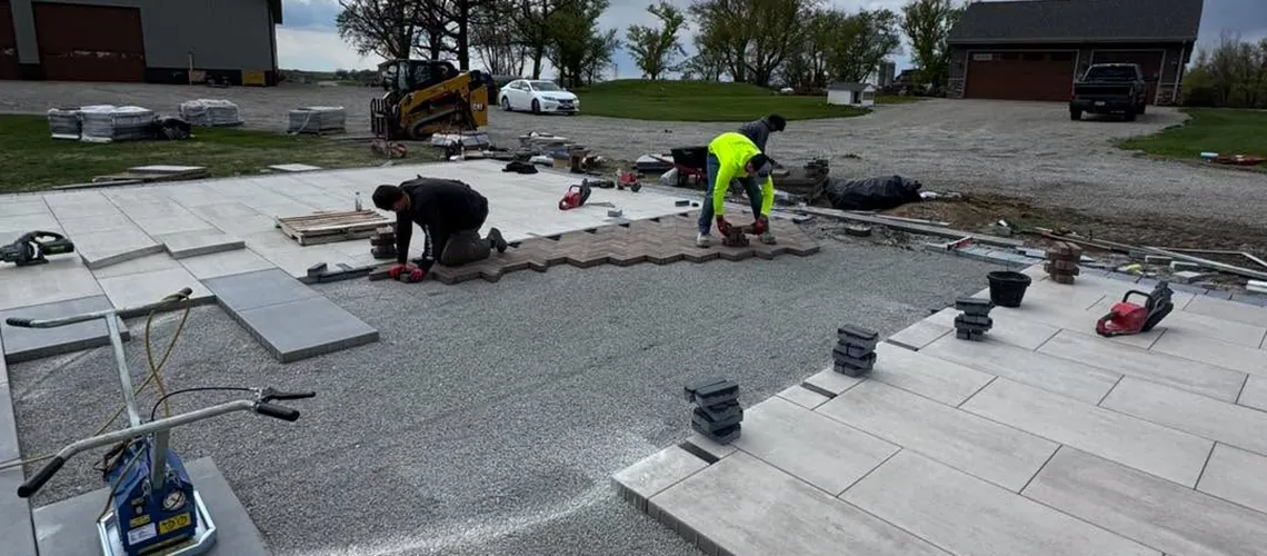 Crew setting large-format pavers around a compacted gravel base on a new patio