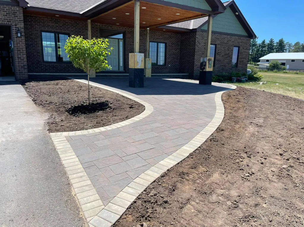 Curved paver walkway with a light border leading to a home's covered front entry